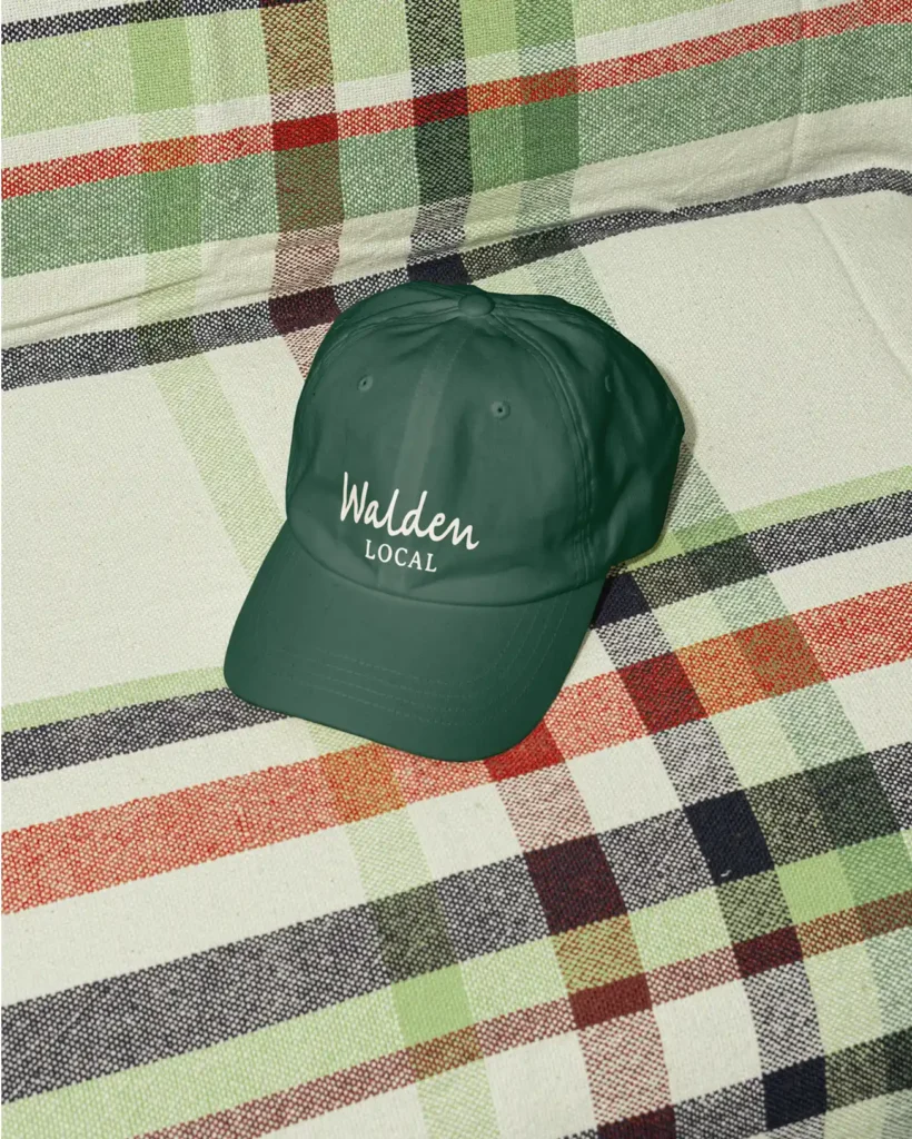 Walden Local hat on plaid fabric background, styled for CPG brand identity.