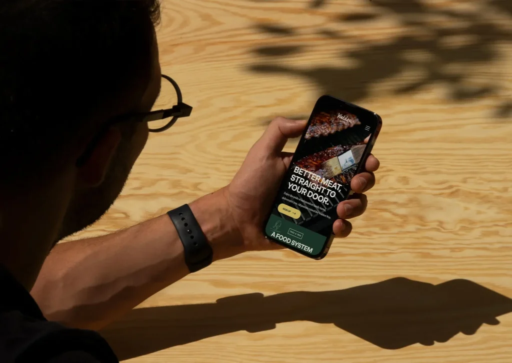 Man viewing Walden Local homepage on phone, showing DTC marketing visuals.