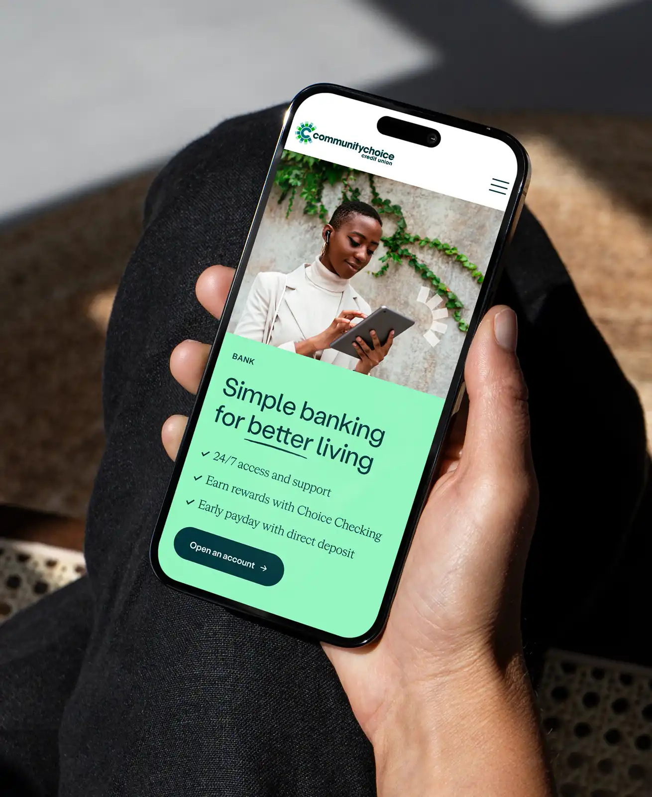 A person holds a smartphone displaying a banking app with a woman using a tablet and text promoting simple banking services and features.