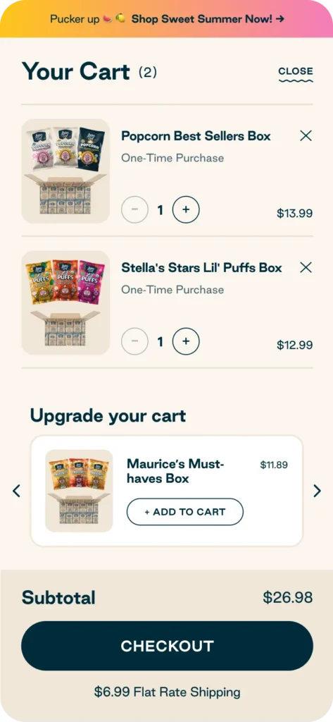 Online shopping cart showing two snack boxes with prices, an option to add another box, subtotal of $26.98, $6.99 flat rate shipping, and a Checkout button.