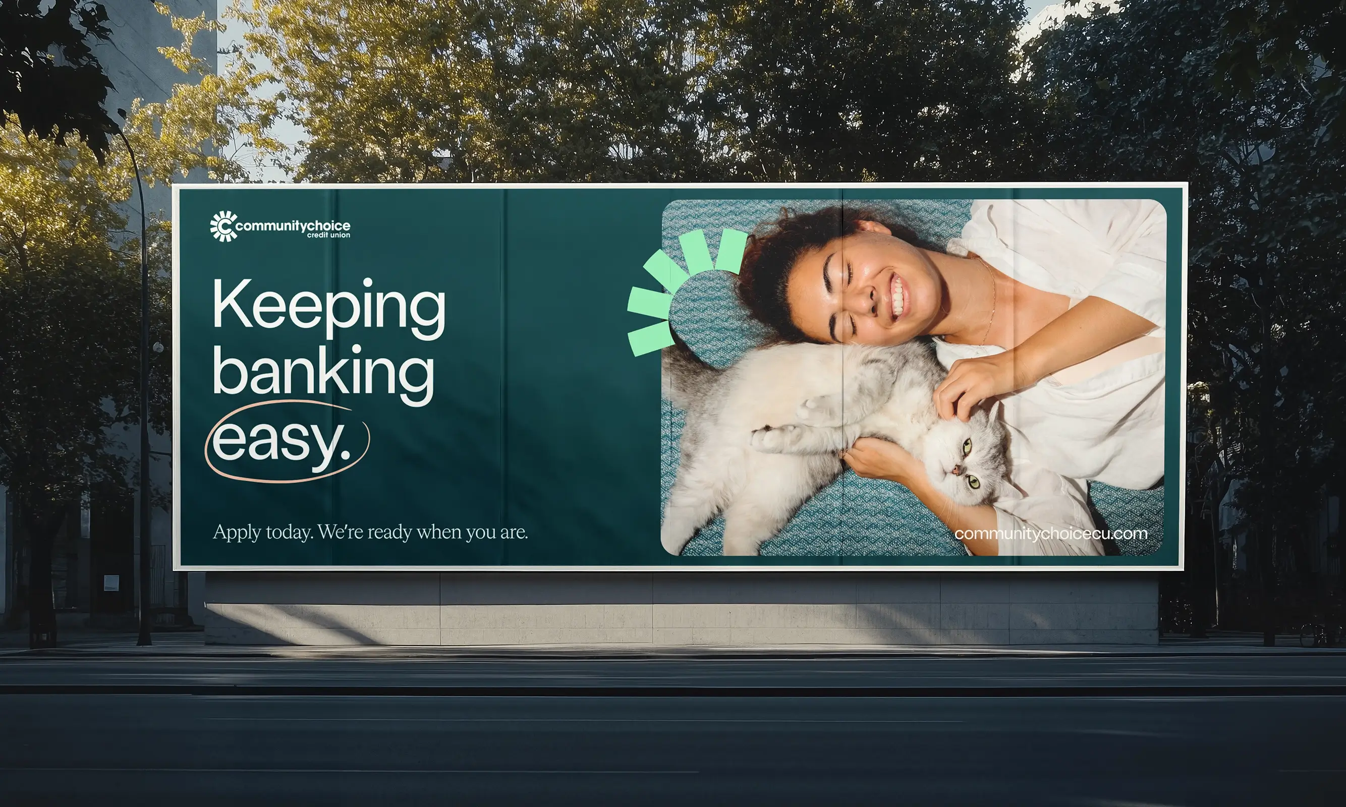 A billboard shows a smiling woman lying on a blue couch, cuddling a fluffy cat, with text reading Keeping banking easy and banking information on the left.