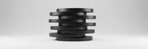 A stack of eight black, round disks arranged slightly askew against a plain gray background.