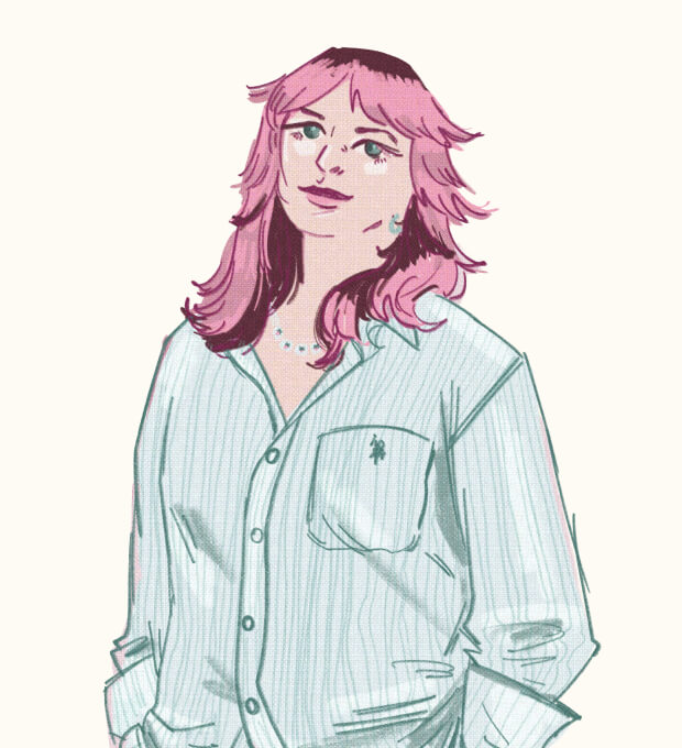 A person with pink hair wearing a striped button-up shirt, standing with hands in pockets and smiling slightly.